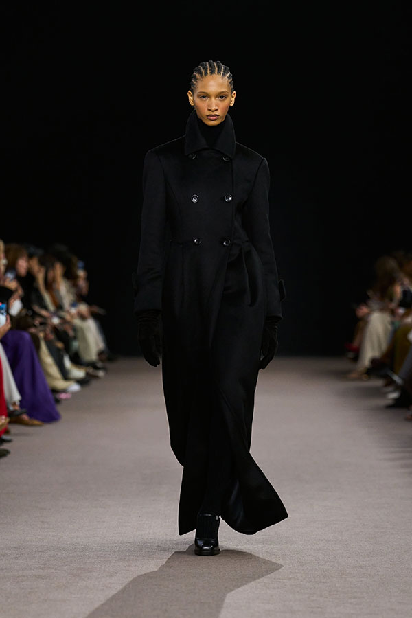 Desfile Max Mara otoño-invierno 2025 - Look negro con abrigo de camello, guantes largos de napa efecto ante y merceditas.