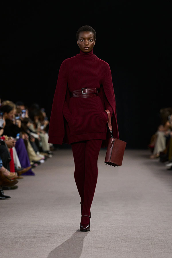 Desfile Max Mara otoño-invierno 2025 - Look cereza con vestido tipo capa, cinturón, bolso bandolera pequeño y merceditas