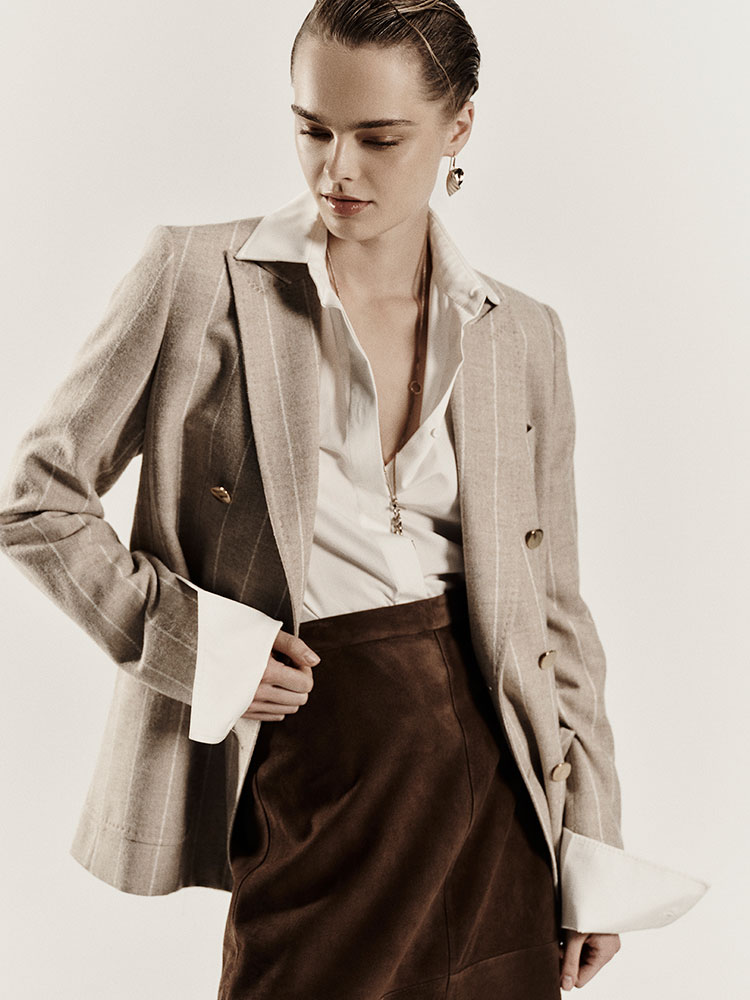 Modelo con el blazer con cierre cruzado Max Mara Sartoriale beige de alpaca y lana, con camisa clara y pantalón marrón.